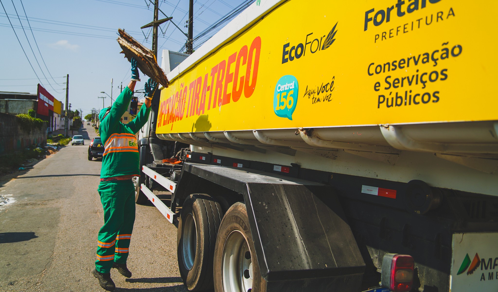 funcionário da ecofor joga lixo dentro caminhão tira-treco